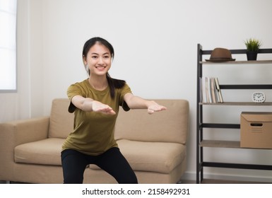 Young Beautiful Fitness Asian Woman Doing Squat Sit Up Exercise Workout At Home. Attractive Female Warming Up Body Training Wearing Sportswear. Side View Sporty Girl Stretching Warm Up Cardio Body.