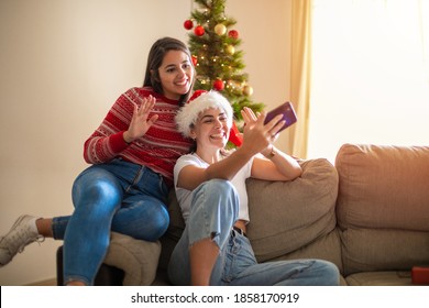 Young beautiful gay couple smiling happy and confident. Sitting on the floor using smartphone in a video call around christmas tree at home - Powered by Shutterstock