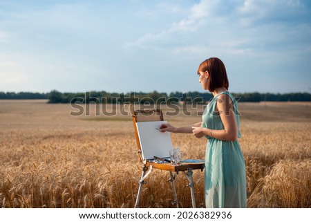 Young beautiful girl artist drawing a painting. Artist making preliminary sketches with a pencil