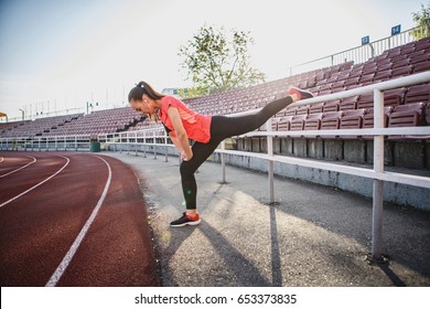 Young, beautiful girl athlete in sportswear doing warm-up at the stadium