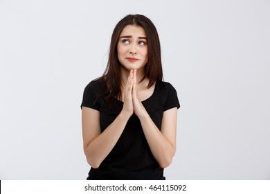 Young Beautiful Girl In Black T-shirt Praying Hopefully Over White Background