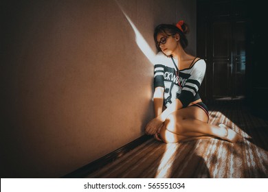 Young Beautiful Girl With Blond Hair Is Sitting On The Floor And Listening Melancholy Music In The Dim Light Of The Room