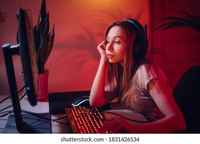 Young Beautiful Girl Is Bored At The Computer. The Woman Gamer Is Tired. Evening Entertainment On The Internet. Teen Surfing The Internet