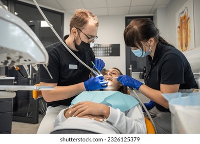 young beautiful girl at the dentist with an assistant receives treatment with the help of the latest equipment. dentistry - Powered by Shutterstock