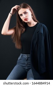 Young Beautiful Girl Dressed In A Black Jacket And Jeans Posing In Studio. Office Modern Style. Young Elegant Business Woman.