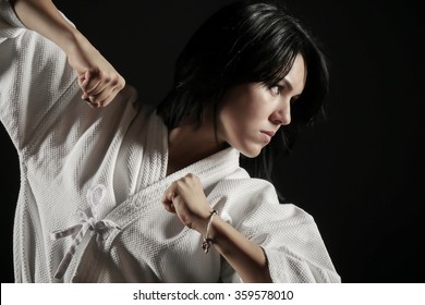 Young, beautiful girl dressed in hakama practicing Aikido in a dark gym