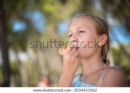 Young beautiful girl eating ice cream cone by the beach on a sunny day of summer on holidays