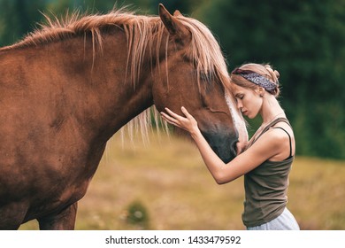 Young beautiful girl hugs horse at nature.