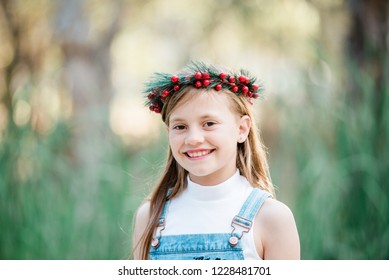 Young Beautiful Girl With Long Brown Hair Celebrating An Australian Summer Christmas Wearing Holly Berry Wreath Flower Crown Denim Overalls  Smiling Outdoors