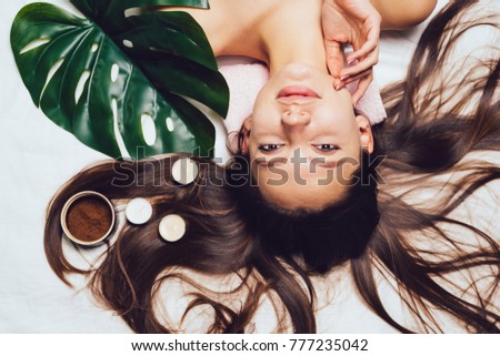 young beautiful girl with long hair arranged a day spa, candles and coffee scrub