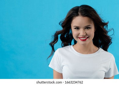 Young beautiful girl looking at the camera and smiling. Lady develops hair from the wind. She has a flawless, dazzling smile. The concept of fashion, beauty, advertising, models, emotions