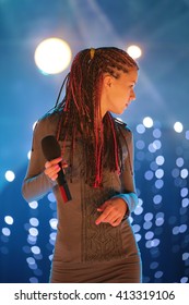 Young Beautiful Girl With A Microphone In Hand, Singing On Stage In The Rays Of Light