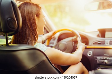 Young Beautiful Girl With A Nice Smile Driving A Car. Rear View.