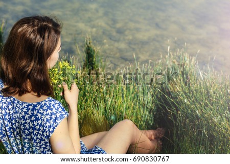 Young beautiful girl on the river bank with flowers in her hands. waiting for her beloved