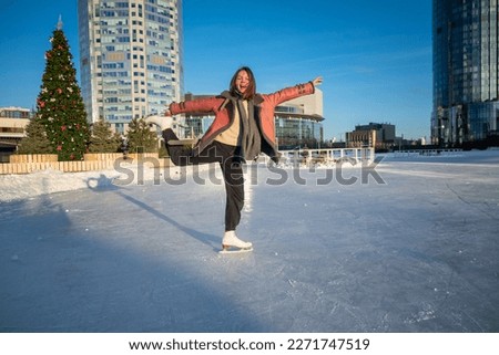 a young beautiful girl on skates in a sheepskin coat on a skating rink against the backdrop of the metropolis and the rays of the sun