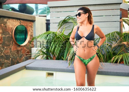 Brunette surfer woman with top and bikini holding surfboard