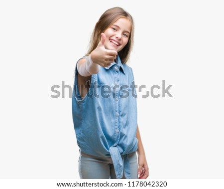 Young beautiful girl over isolated background doing happy thumbs up gesture with hand. Approving expression looking at the camera with showing success.