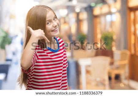 Young beautiful girl over isolated background smiling doing phone gesture with hand and fingers like talking on the telephone. Communicating concepts.