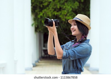 Young beautiful girl photographer taking a photograph of a close-up. Against the background of a green wall of plants. Holds a vintage camera. The mirrorless camera. - Powered by Shutterstock