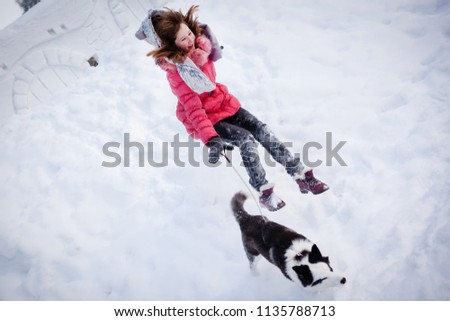 Young beautiful girl playing with siberian husky dog in the winter park