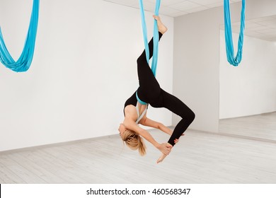 Young beautiful girl practicing aerial yoga in gym. 