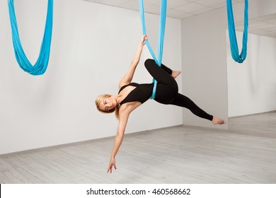 Young beautiful girl practicing aerial yoga in gym.