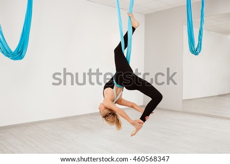 Young beautiful girl practicing aerial yoga in gym. 