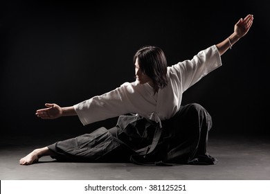 Young, beautiful girl  practicing Aikido in a dark gym