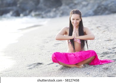 Young beautiful girl practicing yoga on the beach