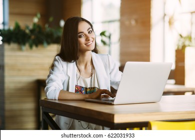 Young beautiful girl preparing for exams with laptop, surfing articles about innovations in web development, programming and design. Business lady working through internet in digital marketing field.