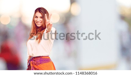 young beautiful girl with a proud, happy and confident expression; smiling and showing off success while gesturing victory, giving an "achiever" look, celebrating triumphantly.