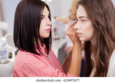 young, beautiful girl put on make-up in a beauty salon - Shutterstock ID 613497677