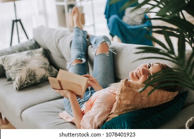 Young beautiful girl reading a book on the couch.