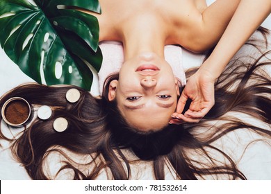 young beautiful girl relaxes, scented candles, coffee scrub, day spa