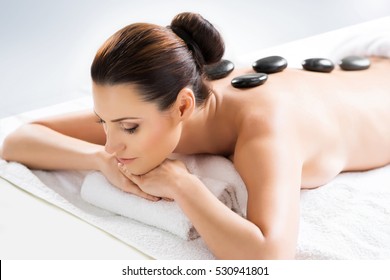 Young and beautiful girl relaxing in Christmas spa salon. Massage therapy, healing medicine and health care concept. 