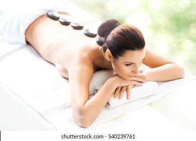 Young and beautiful girl relaxing in spa salon. Massage therapy over seasonal summer or spring background. Healing medicine and health care concept. 