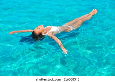 Young beautiful girl relaxing while floating in the sea.  
