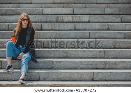 Young beautiful girl sitting on the steps with coffee in glasses.