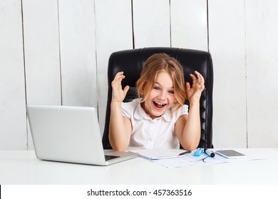Young beautiful girl sitting at working place, laughing in office.