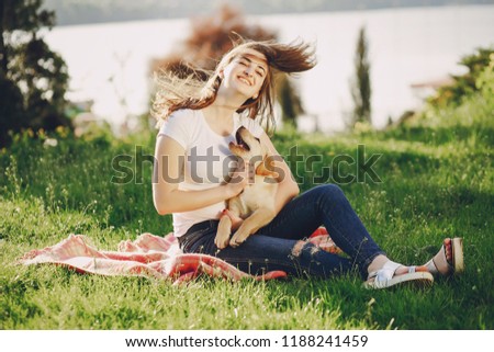 Young beautiful girl in a summer sunny park playing with a dog