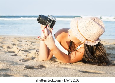 young beautiful girl taking photos on beach with camera photograph