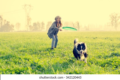 Young beautiful girl throwing to her dog in a park at sunset - Asian woman playing with her dog