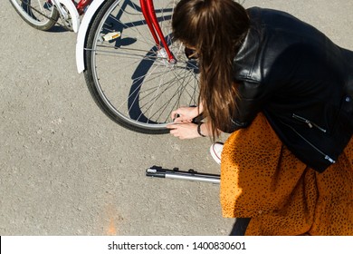 
Young beautiful girl trying to pump up the wheel of the bike. A girl holds a pump in her hands and tries to pump up the bike's camera. The girl repairs a bicycle on the street. Bike breakdown - Powered by Shutterstock