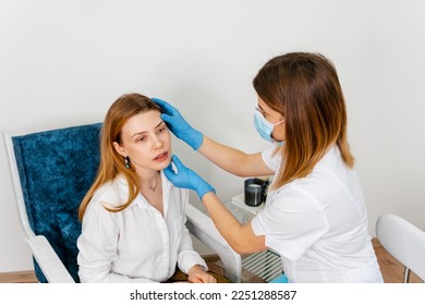A young beautiful girl undergoes a medical examination in a cosmetology clinic. Female doctor is talking with young female patient. Doctor talking to a young woman patient on a medical clinic. - Shutterstock ID 2251288587
