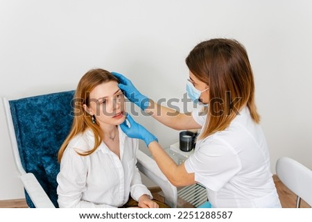 A young beautiful girl undergoes a medical examination in a cosmetology clinic. Female doctor is talking with young female patient. Doctor talking to a young woman patient on a medical clinic.