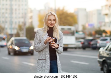 Young beautiful girl is walking around the city and drinking coffee