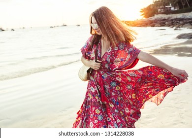 Young beautiful girl wearing boho maxi dress walking on sand. Summer fashion clothes for the beach.