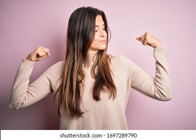 Young beautiful girl wearing casual turtleneck sweater standing over isolated pink background showing arms muscles smiling proud. Fitness concept. - Shutterstock ID 1697289790