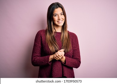 Young beautiful girl wearing casual sweater over isolated pink background with hands together and crossed fingers smiling relaxed and cheerful. Success and optimistic