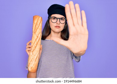 Young beautiful girl wearing fashion french beret holding fresh baked bread baguette with open hand doing stop sign with serious and confident expression, defense gesture
